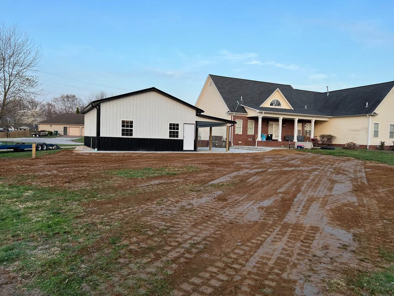 Freshly graded property surrounding a home and detached garage